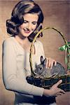 Sweet, beautiful, adorable, happy brunette woman is holding a easter basket with fluffy, cute rabbit.
