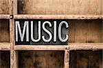 The word "MUSIC" written in vintage metal letterpress type in a wooden drawer with dividers.