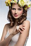 Attractive, brunette sprig woman in white top and wreath of flower oh head and little bird on the finger.