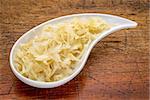 sauerkraut side dish - a white teardrop shaped bowl against rustic wood