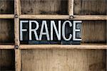 The word "FRANCE" written in vintage metal letterpress type in a wooden drawer with dividers.