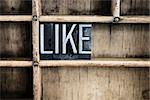 The word "LIKE" written in vintage metal letterpress type in a wooden drawer with dividers.