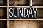 The word "SUNDAY" written in vintage metal letterpress type in a wooden drawer with dividers.