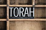 The word "TORAH" written in vintage metal letterpress type in a wooden drawer with dividers.