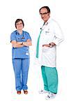Female doctor standing with crossed arms while male doctor posing with hands in pocket