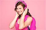 A beautiful young schoolgirl listening to music isolated over pink background