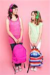 Beautiful teenagers standing with bag in hand and listening to music through headphones