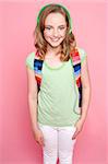 Cute girl with backpack and headphones smiling at camera in isolation