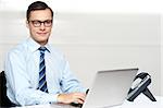 Handsome corporate male tying on laptop. working in office