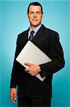 Businessperson carrying a laptop posing against blue background