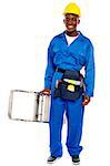 African repairman holding stepladder with tool bag around his waist isolated against white background