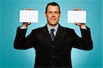 Smiling businessman showing two blank white placards to camera