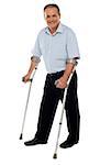 Senior man standing with the help of crutches. Recovering from an accident