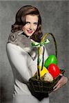 lovely easter portrait of pretty woman with vintage hair-style taking basket with colorful eggs and tender rabbit on her shoulder