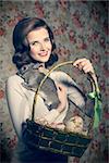 funny easter shoot of smiling vintage girl with colorful eggs in basket and fluffy rabbit