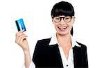Cheerful bespectacled woman holding up her cash card. All on white background