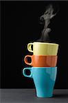 Three colorful mug with steam on top of one another