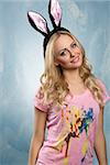 Beautiful, charming, smiling woman with blonde, curly hair and rabbit ears, wearing pink t-shirt and nice dark make up.
