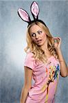 Beautiful, charming, playful blonde woman with curly hairstyle and fluffy rabbit ears wearing pink t-shirt.