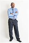 Full body Indian businessman arms crossed standing on plain background with shadow