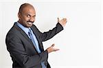 Indian businessman hands showing something on copy space, standing on plain background.