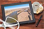 aerial landscape photography concept - reviewing aerial pictures of  the South Platte RIver in Colorado on a digital tablet with a drone rotor and cup of coffee, screen picture copyright by the photographer