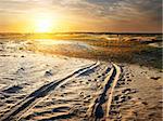 Auto traces in a sand desert at sunset