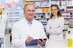 Senior pharmacist writing on clipboard at the hospital pharmacy