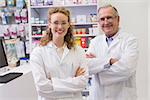 Smiling pharmacists with arms crossed in the pharmacy