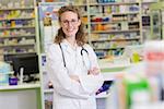 Phamacist in lab coat with stethoscope and arms crossed in the pharmacy