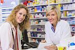 Pharmacist and costumer looking at camera at pharmacy