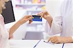 Pharmacist giving credit card to costumer at pharmacy