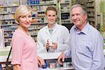 Pharmacist and costumers smiling at camera at pharmacy