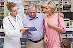 Pharmacist showing tablet pc to costumers at pharmacy