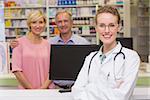 Pharmacist and costumers smiling at camera at pharmacy