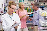 Pharmacist writing on clipboard at the hospital pharmacy