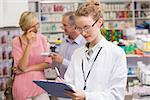 Pharmacist writing on clipboard at the hospital pharmacy