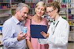 Pharmacist showing clipboard to costumers at pharmacy