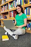 Student sitting on floor in library using laptop at the university