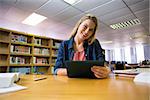 Student studying in the library with tablet at the university
