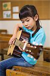 Cute pupil playing the guitar at elementary school