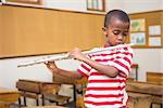 Cute pupil playing flute in classroom at the elementary school