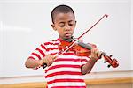 Focus pupil playing violin in classroom at elementary school