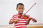 Happy pupil playing violin in classroom at the elementary school