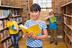 Cute pupil smiling at camera in library at elementary school