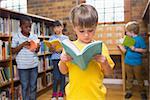 Cute pupils reading books at library at elementary school