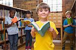 Cute pupils reading books at library at elementary school