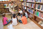 Cute pupils and teacher having class in library at the elementary school