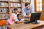 Teacher and pupils using computer at library at elementary school