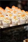 Close-up of Cupcakes with Orange Icing Flowers on Dessert Table